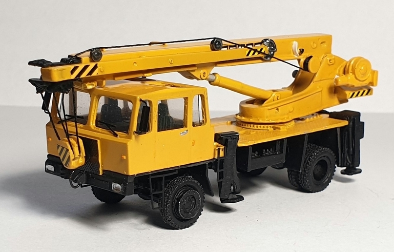 IFA Takraf ADK 125-3 autojeřáb žlutý (model) – pohled zepředu zleva s výložníkem a opěrami.